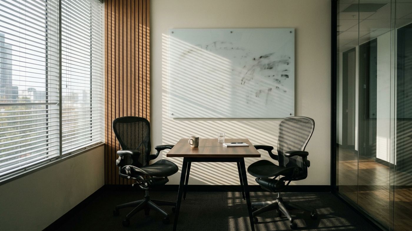 Empty modern meeting room with whiteboard and two chairs facing each other